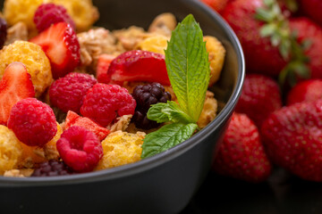 Mueslis with berries in a black  cup on the table, macro