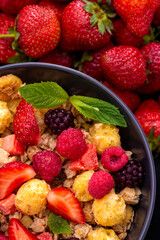 Mueslis with berries in a black  cup on the table, macro