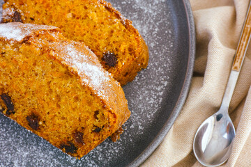 Gray plate with  two pieces of carrot cake and spoon on beige napkin.