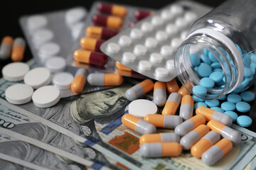 Pills and capsules on US dollar bills. Concept of health care, pharmaceutical business, drug prices...