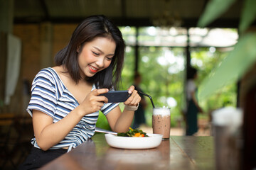 Asia woman taking photo food on dishes in restaurant