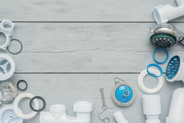Shower plastic siphon parts on white wooden floor background.