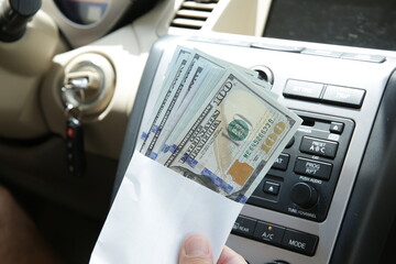 Dollars cash in an envelope against the background of a car interior. Concept of car sale, purchase and leasing.