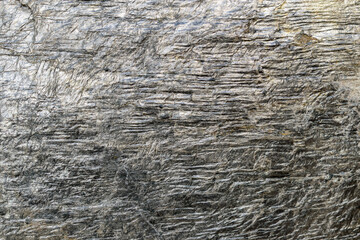 Gold-antimony ore for backdrop. Stibnite with gilded veins. Close-up. Structure of shales. Concept of industrial mining of precious metal.