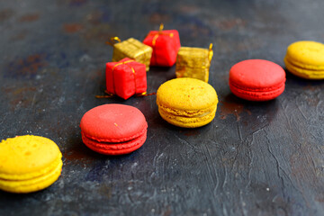 Obraz na płótnie Canvas Red and yellow macaroons and decorative gift boxes on a dark blue rustic background.