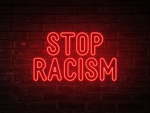 Stop racism - red neon light word on brick wall background
