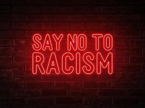 Say no to racism - red neon light word on brick wall background