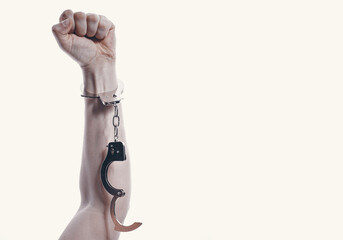 hand on a white background clenched into a fist with handcuffs fastened on it