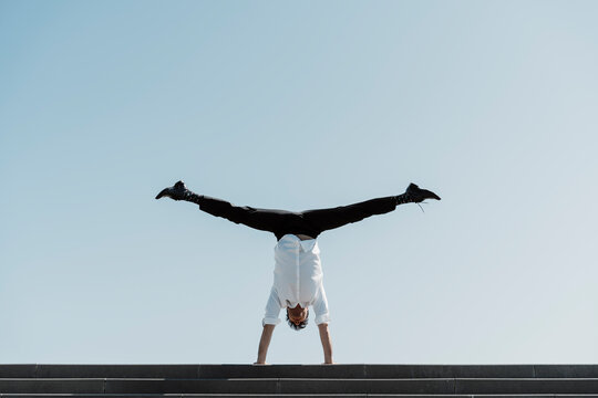 Businessman doing a handstand on top of stairs