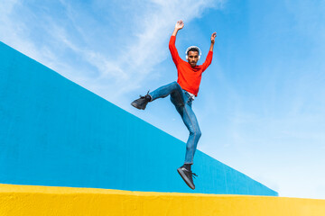 Young man with headphones, listening music, dancing on yellow wall