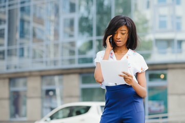 A pretty African american business woman talking on a cell phone at office building