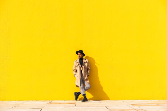 Young man dancing in front of yellow wall