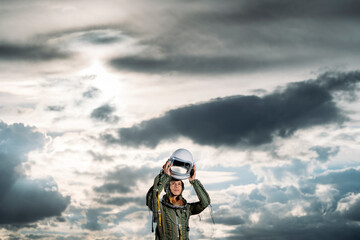 Man posing dressed as an astronaut on a meadow with dramatic clouds in the background