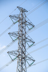 A vertical shot of an electricity pylon against a blue sky.