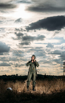 Man posing dressed as an astronaut on a meadow with dramatic clouds in the background