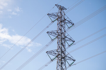 A horizintal shot of an electricity pylon against a blue sky.