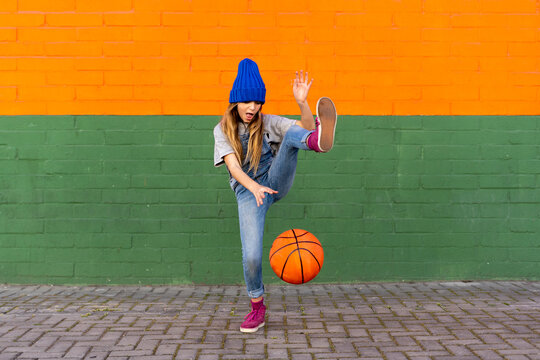 Young girl playing basketball, dribbling and lifting leg