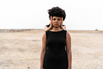 Woman's hands covering ears of another woman standing in bleak landscape