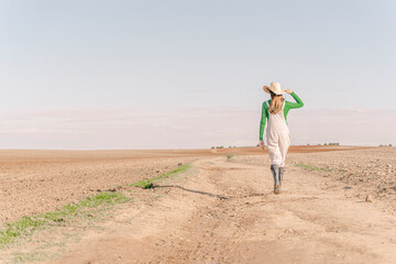 Young woman walking on dry field, rear view
