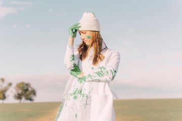Young woman putting green painted hand on her forehead, thinking
