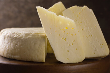 Slices of semi cured Brazilian Canastra chesse close in wood background