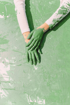 Green hands of young woman on green painting