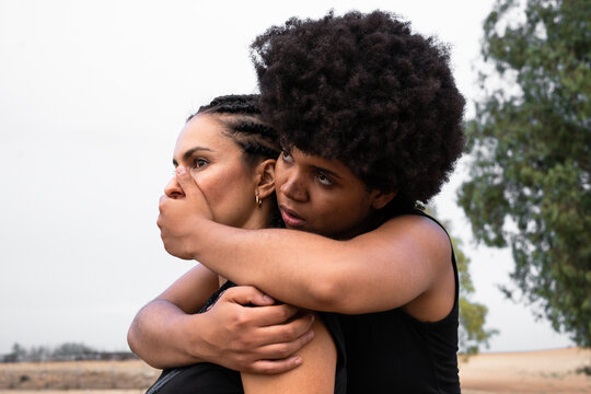 Woman covering mouth of other woman with her hand