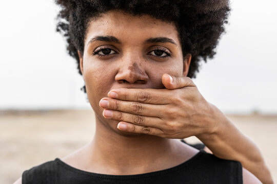 Woman's hand covering mouth of another woman, close-up