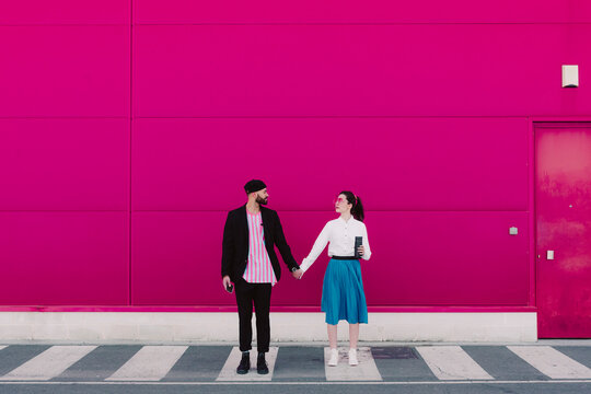 Couple standing on crosswalk, face to face and holding hands