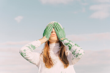 Young woman covering eyes with green hands