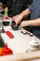 Fototapeta premium A professional chef punishes rolls with mayonnaise and caviar