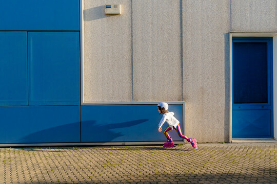 Little girl with safety helmet inline skating at sunlight