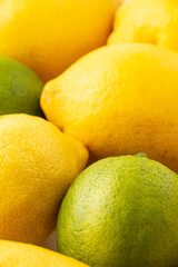 Close-up of various lemons and limes, with selective focus, vertical