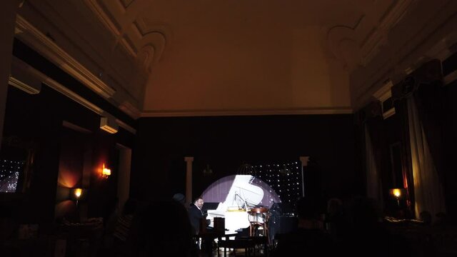 Wide shot of a pianist performing his own music in club interior background. A classic and jazz music concert at night club. 
