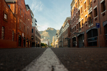 Fototapeta na wymiar historic brick warehouse buildings with empty road with mountain in background lockdown
