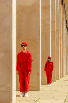Young couple wearing red overalls and hats standing in a row