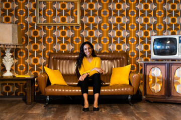 Portrait of smiling woman sitting on couch in vintage living room
