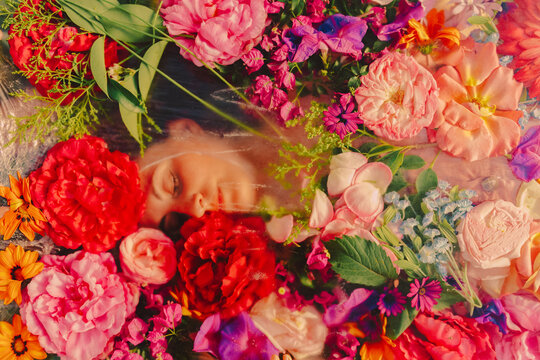 Woman sleeping under glass pane with flowers