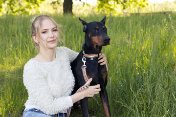 Beautiful girl walks in the park with her dog Doberman, walk with a big dog