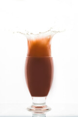 Orange red drink in glass ice fall splash