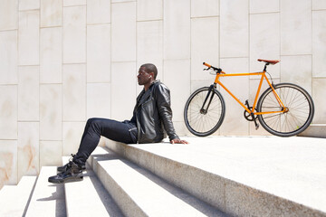 Man sitting on step next to his bike