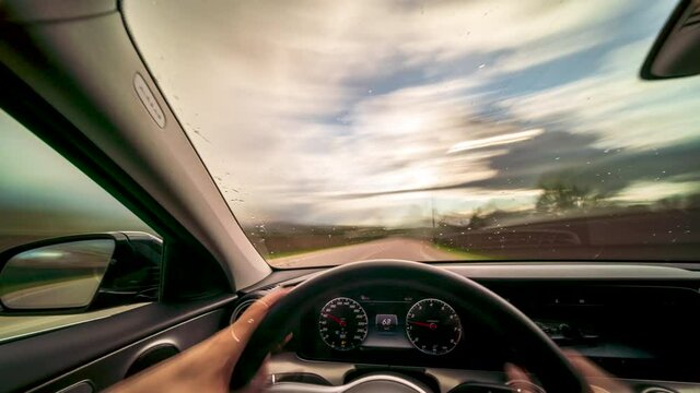 Driver holds both hands on steering wheel as he drives his car Long exposure Timelapse