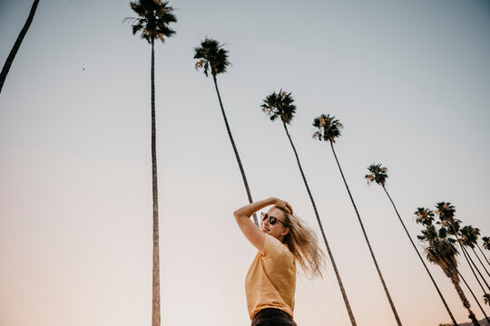 Low angle view of happy young woman under palm trees