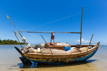 Fototapeta na wymiar Fishing boat at low tide on the beach in Boipeba Island, Brazil 