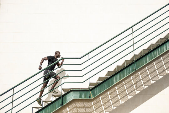 Man in black sportswear running up staircase