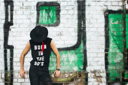 Young man covering his face with a hat wearing t-shirt with saying 'Born in the 90s'