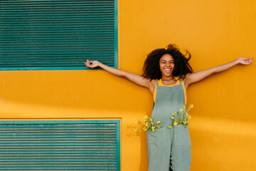 Portrait of carefee young woman wearing overalls with flowers in pockets