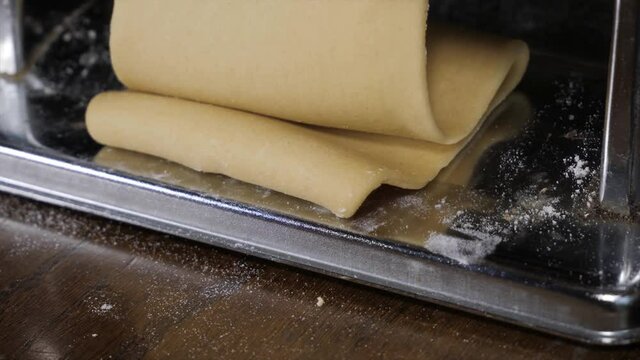 Flattened dough in pasta machine close-up Italian lasagna sheets making at home