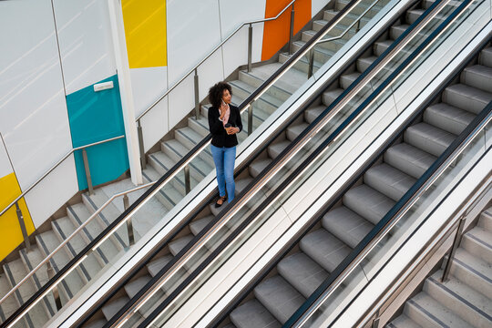 Businesswoman on the phone standing on escalator