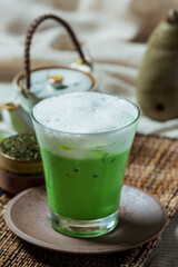 Green tea iced in a tall glass with cream topped with iced green tea. Decorated with green tea powder.